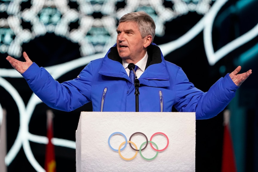 President of the International Olympic Committee Thomas Bach stands at a podium addressing the crowd at the opening ceremony.