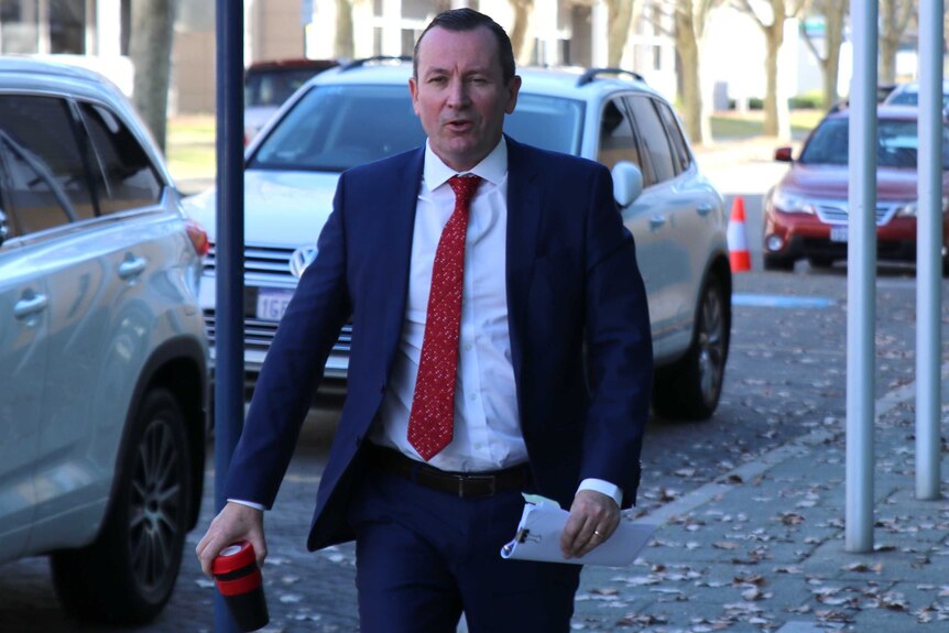 Mark McGowan walks into the ABC studios at East Perth. He wears his trademark red tie, carries a sheaf of documents and a cup.