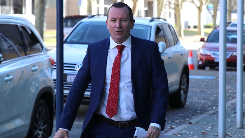 Mark McGowan walks into the ABC studios at East Perth. He wears his trademark red tie, carries a sheaf of documents and a cup.