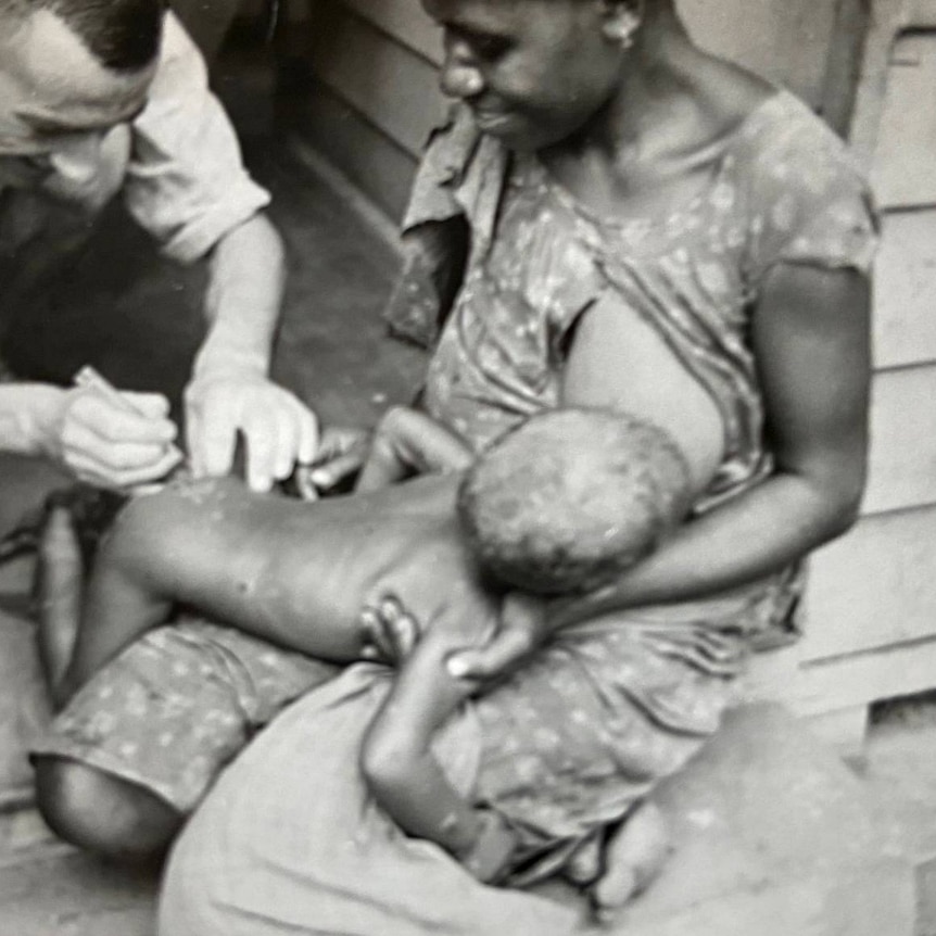 Charles Maclead immunising child in a village
