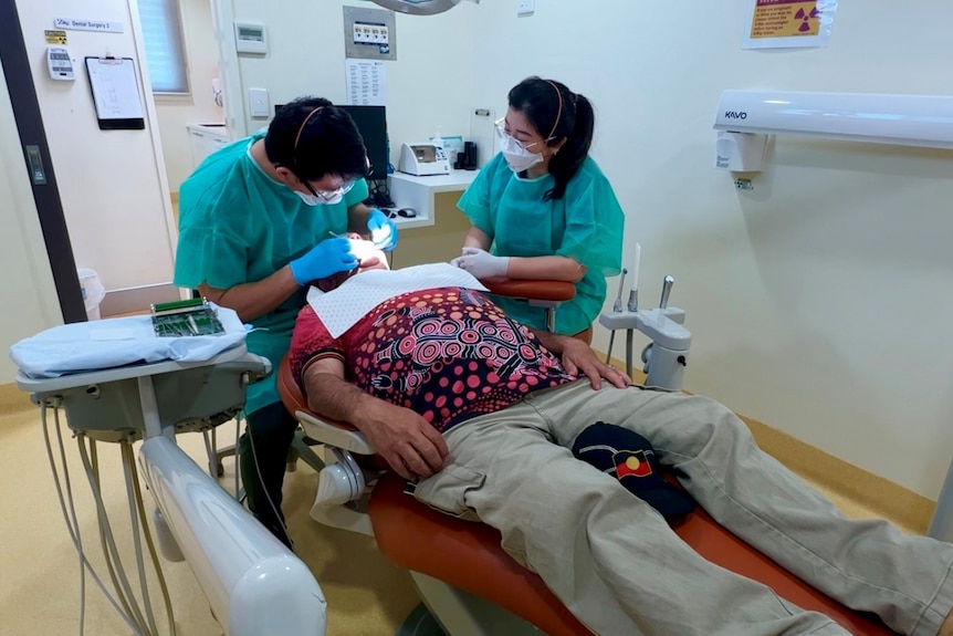 Two student dentists perform a procedure on a man