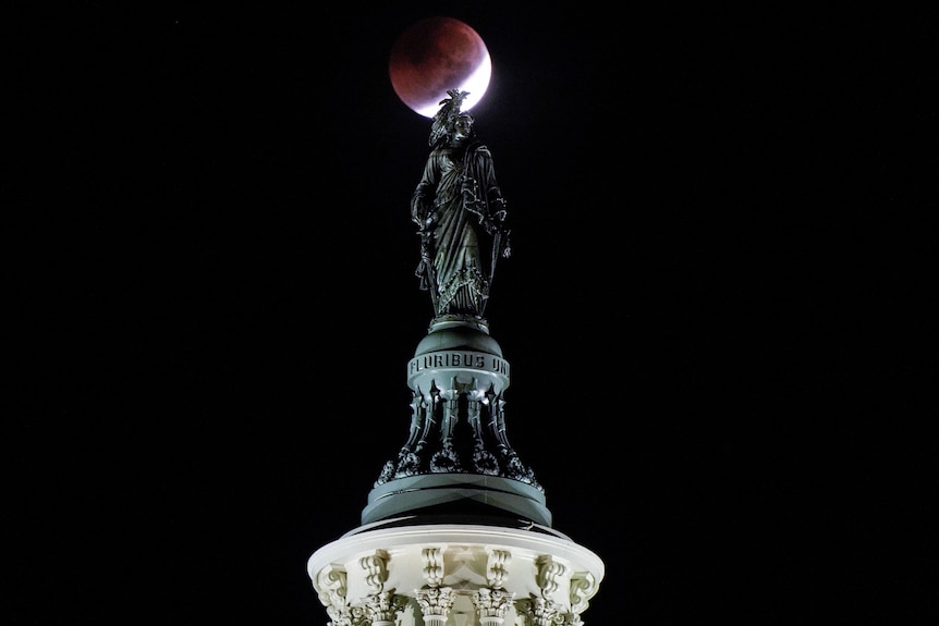 A lunar eclipse is seen behind the Statue of Freedom on the U.S. Capitol Dome in Washington, US.