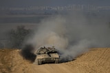 An Israeli tank driving through a dirt road.