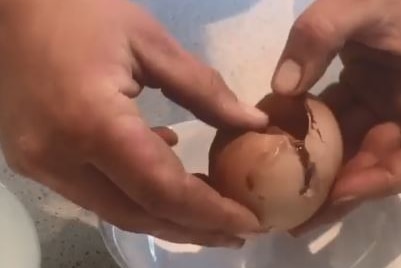 A pair of hands shown cracking open a very large egg.