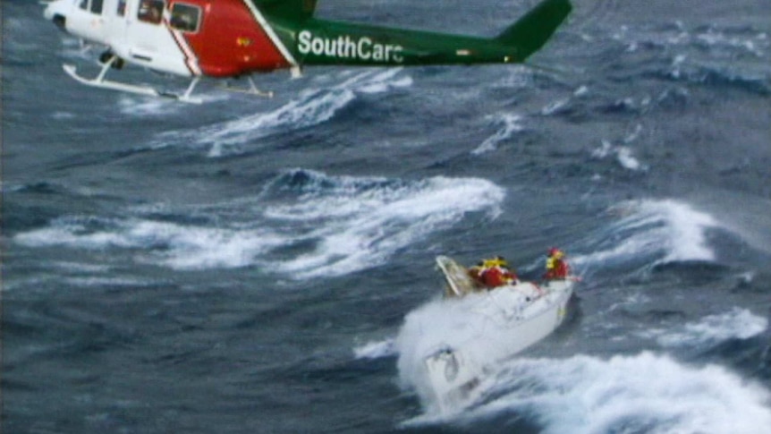 Crew of a dismasted yacht waiting to be rescued from a SouthCare helicopter hovering overhead
