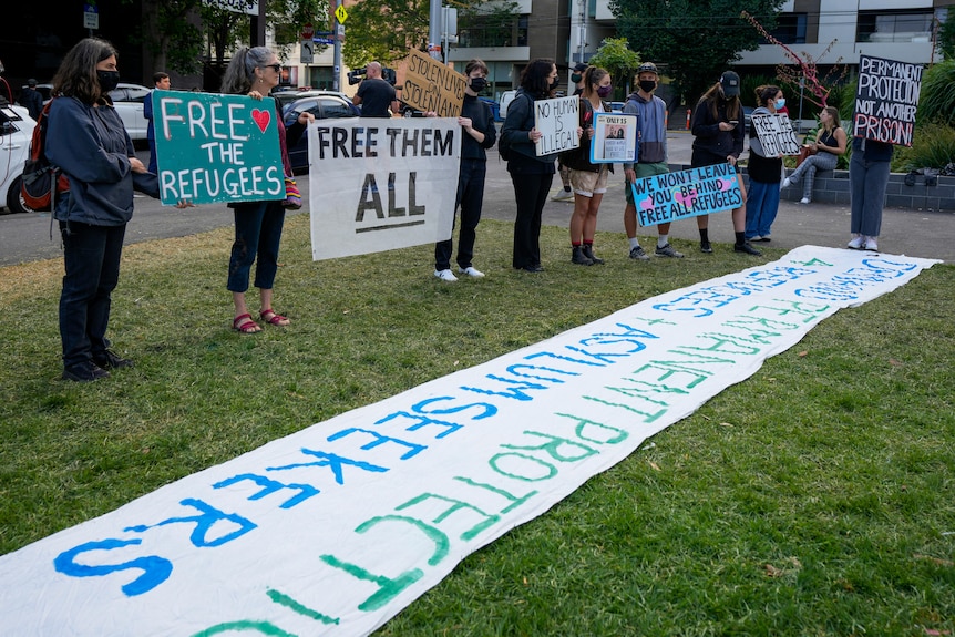 Refugee advocates hold placards advocating for the refugees to be freed from the same detention centre holding Novak Djokovic.