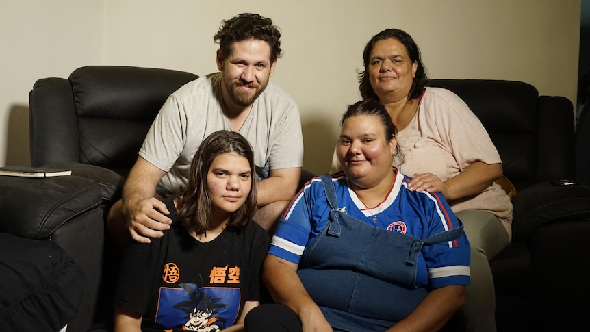 three woman and one man huddle together, smiling for family portrait