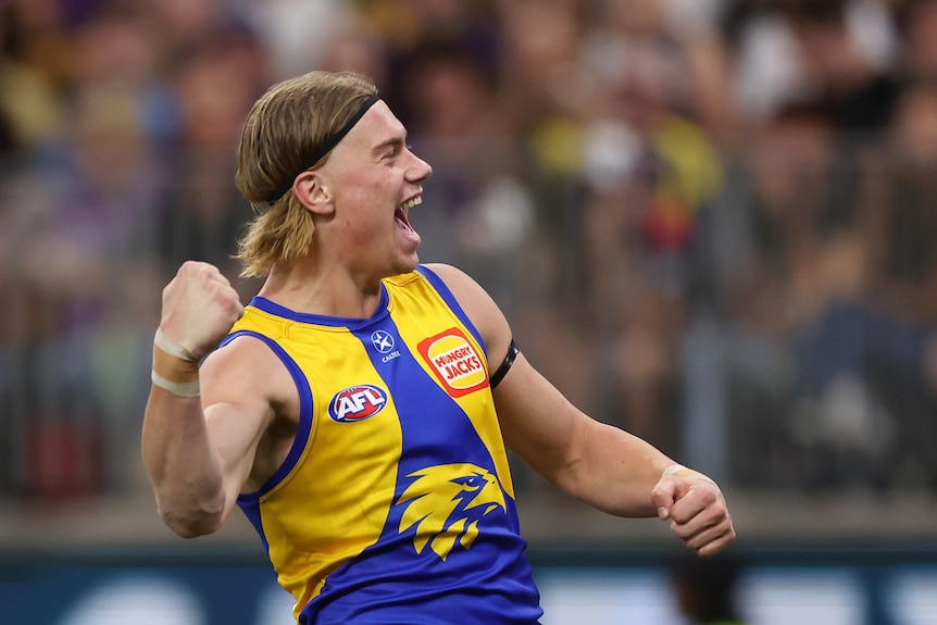An AFL player pumps his first and screams in excitement to a massive crowd