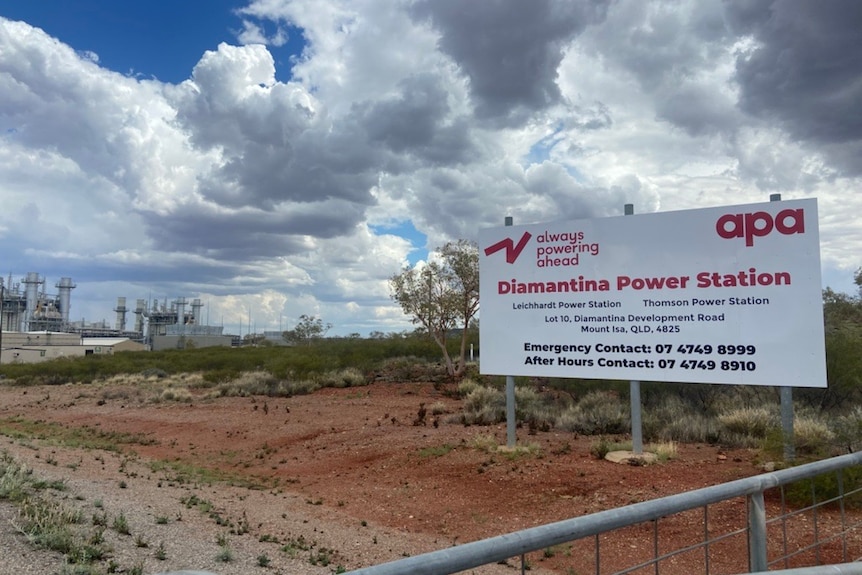 A sign that says "Diamantina Power Station" behind a fence. In the background the outback power facility is visible.