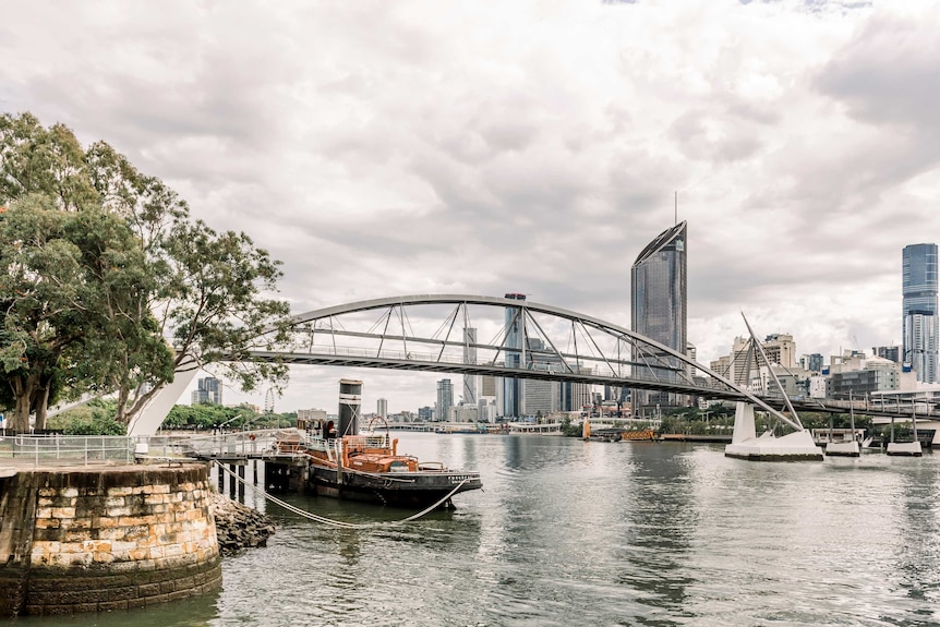 Un vieux bateau amarré le long de la rivière Brisbane à South Brisbane.  Le Goodwill Bridge relie South Brisbane au centre-ville.