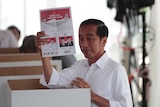 Indonesian president Joko Widodo smiles as he holds up an Indonesian voter card during the election.
