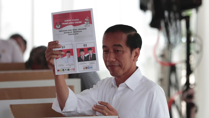 Indonesian president Joko Widodo smiles as he holds up an Indonesian voter card during the election.