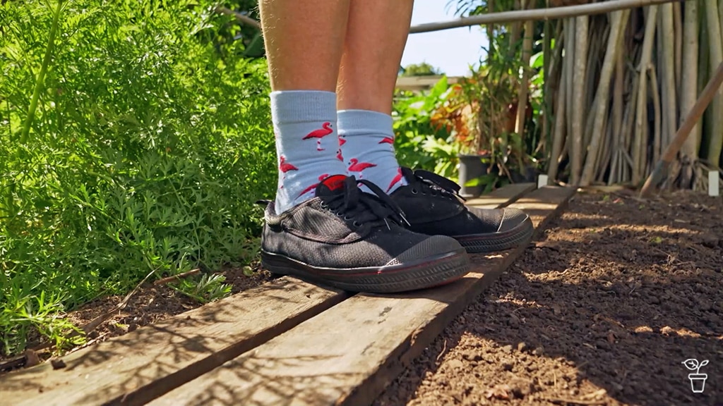 Jerry standing on timber planks in his garden.