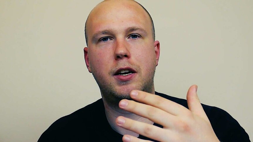 A man with a shaved head gestures