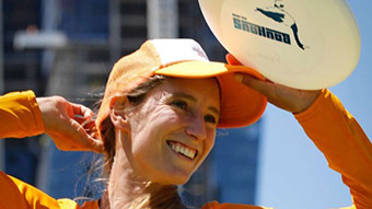 A woman holds a white frisbee disk above her head.