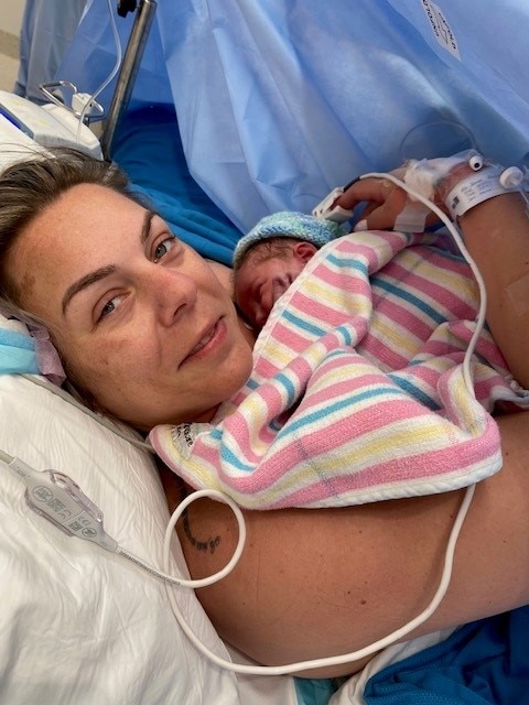 A woman hugging her baby in a hospital bed, having just given birth.