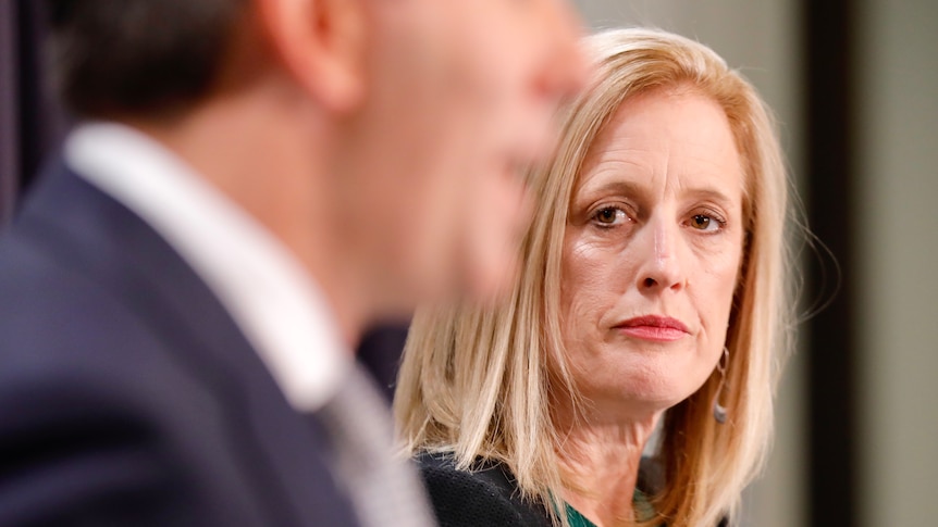 Katy Gallagher looking at Jim Chalmers, who is out of focus, at a press conference