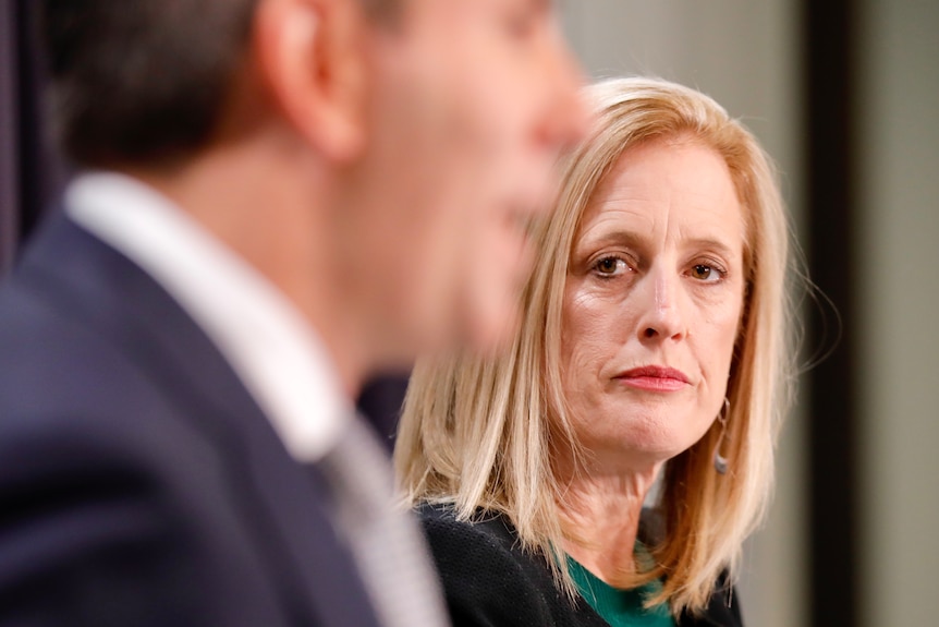 Katy Gallagher looking at Jim Chalmers, who is out of focus, at a press conference