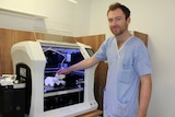 Orthopaedic surgeon Dr Jonathan Davis holding a 3D printed bone inside Mackay Base Hospital's first 3D printer.