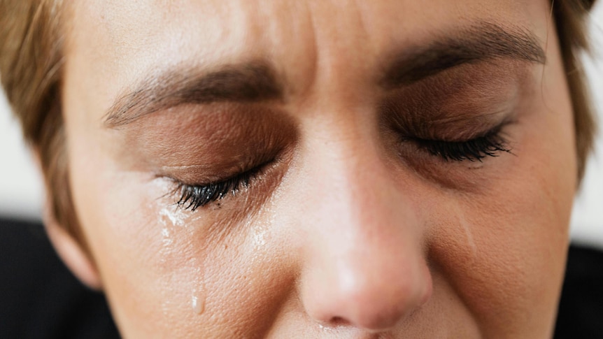 Close up of a woman crying, tears streaming down cheeks