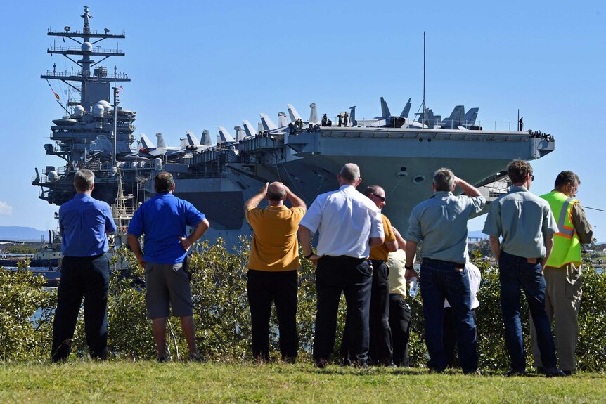 People watch as the USS Ronald Reagan docks at the Port of Brisbane.
