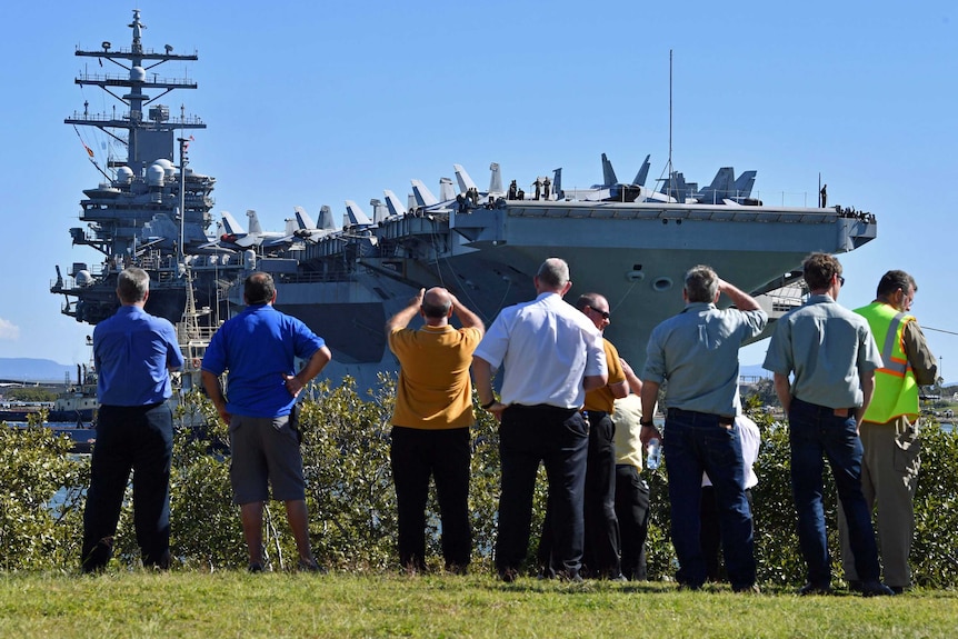 People watch as the USS Ronald Reagan docks at the Port of Brisbane.
