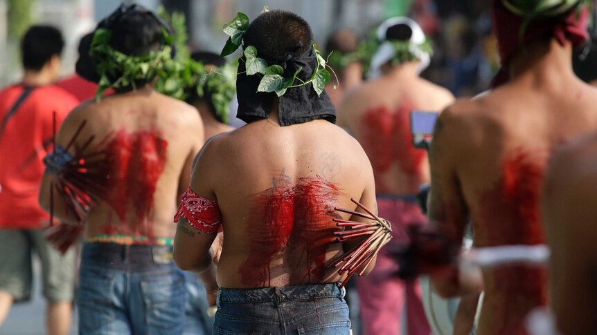 Filipino penitents line up with blood on their backs as they participate in Good Friday rituals.