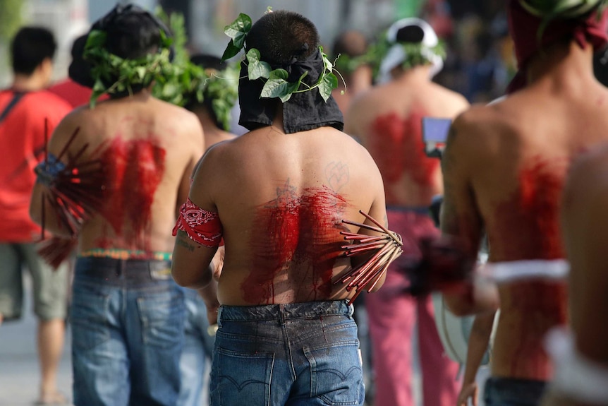 Filipino penitents line up with blood on their backs as they participate in Good Friday rituals.