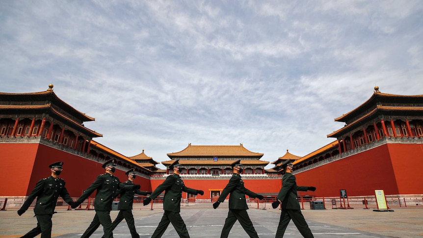 Soldiers wearing protective face masks march past the closed entrance gates to the Forbidden City.