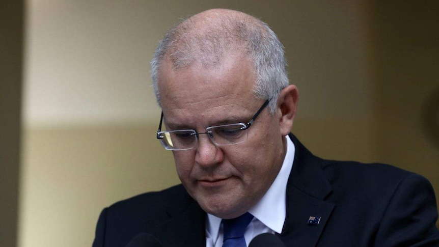 Scott Morrison looks down at his notes while addressing a press conference.