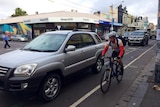 A car passes close by a cyclist on Sydney Road in Brunswick.