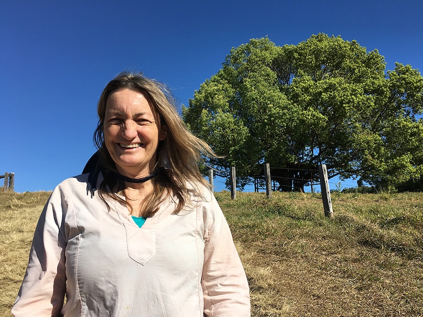 Jo Green stands in front of a large Camphor laurel tree.