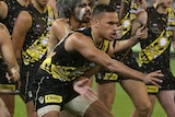 Sydney Stack is front and centre, surrounded by painted Indigenous men and followed by his teammates, doing a traditional dance