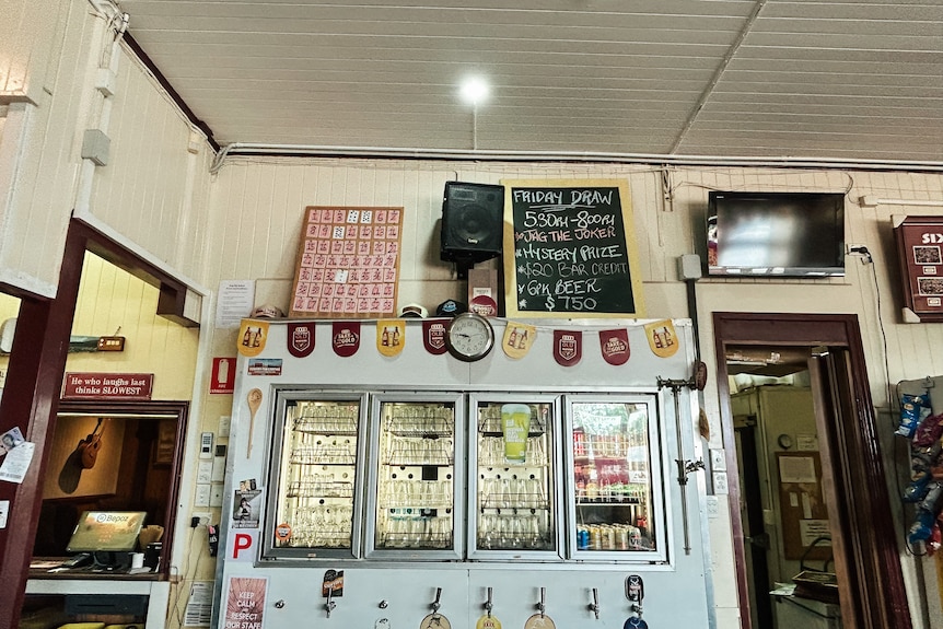 a photo taken from the bar of an outback pub showing glass door fridges and eclectic ornaments and signs on the walls