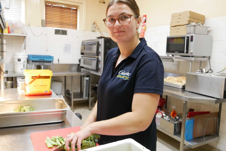 woman with glasses cutting food at restaurant kitchen