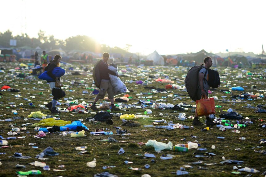 Festival goers walk through a carpet of rubbish.