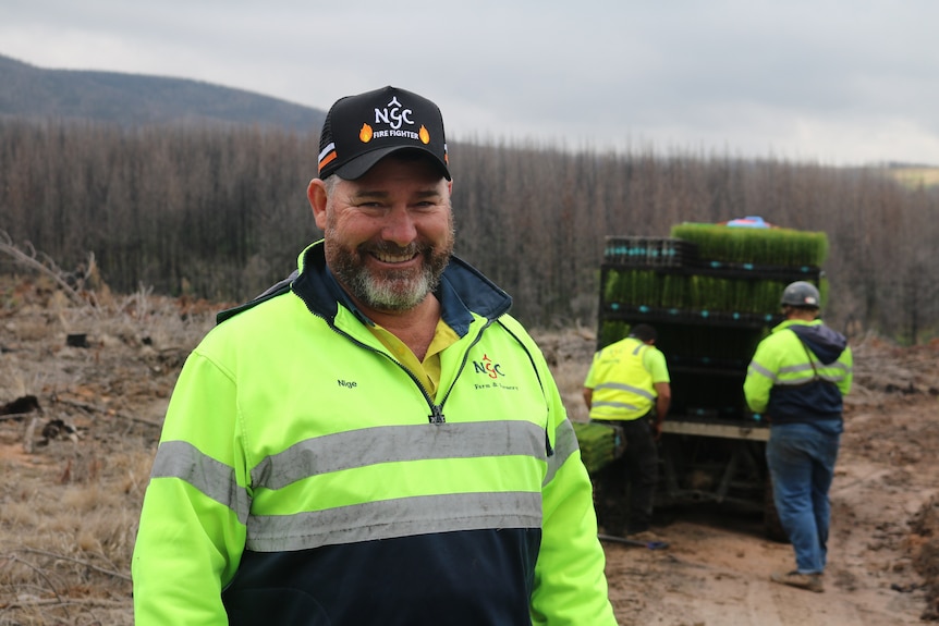 Nigel Grant stands in front of a ATV loaded with pine seedings in a fire damaged forest