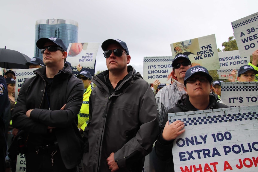 Off duty police officer in plain clothes but wearing caps hold placards arguing for a wage rise.