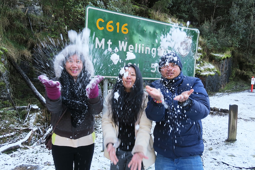 Asian tourists play with snow near summit of Mount Wellington, June 30, 2017.