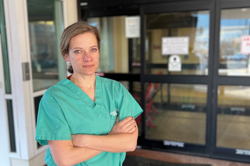 Doctor Morgan Eutermoser in her scrubs at the entrance to the Denver hospital she works at.
