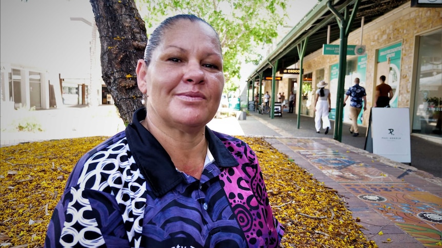 close up of woman wearing Aboriginal print shirt sitting in a shaded city mall