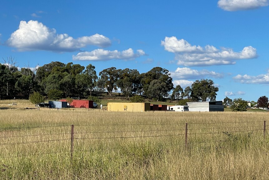 A group of shipping containers in a paddock