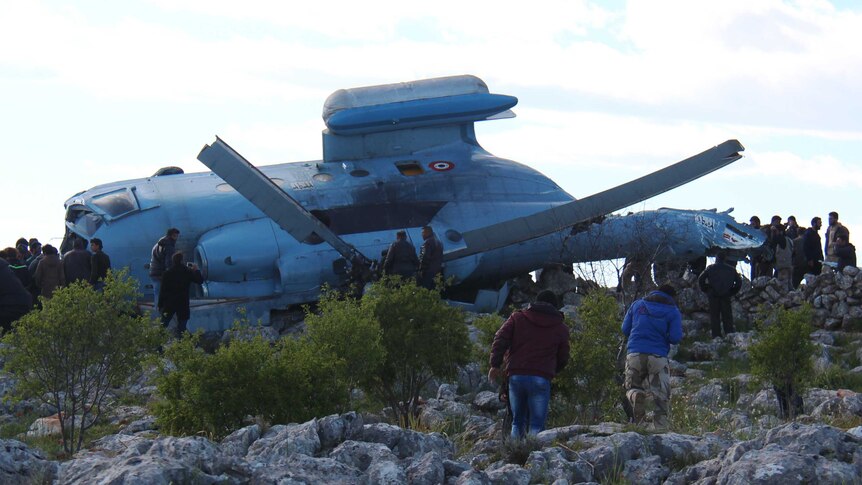 A Syrian military helicopter lies on its side after crashing in Idlib province