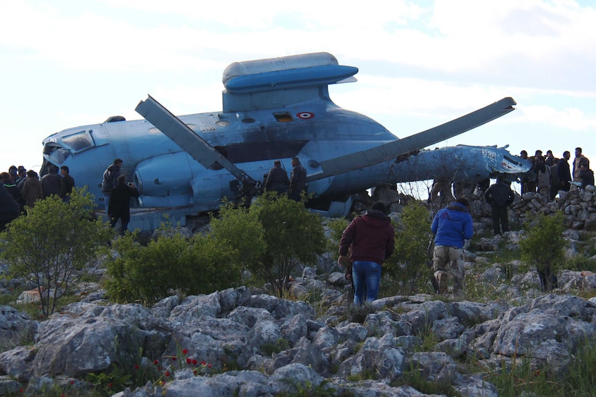 A Syrian military helicopter lies on its side after crashing in Idlib province
