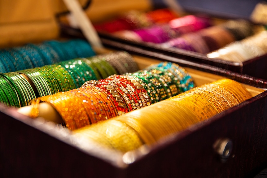 Two boxes of colourful, glittering Indian bangles.