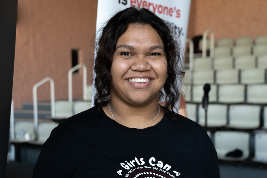 A  young Aboriginal woman with plaited hair, smiling broadly