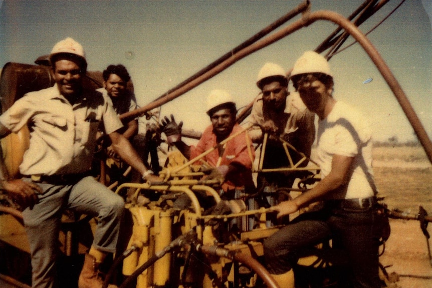 Grupo de trabajadores ferroviarios con cascos en un vagón.