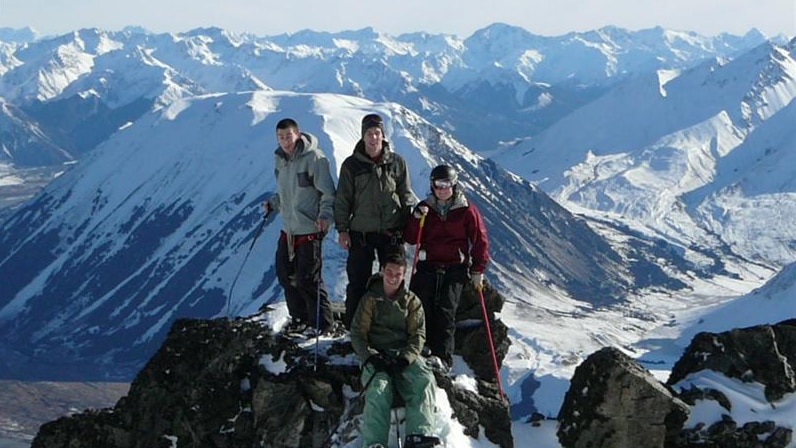Group of four people on top of snowy mountain