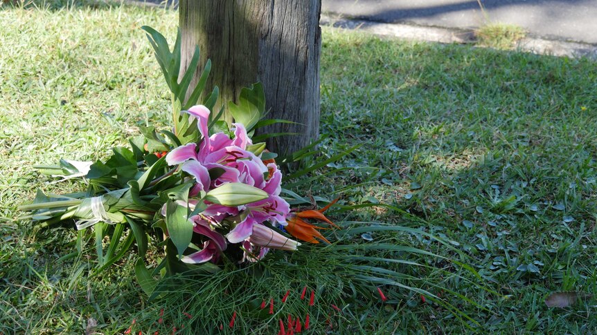 A bouquet lies on the nature strip next to the road.