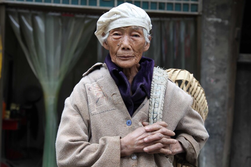 A 91-year-old woman stands on the main street of Changgang, China.